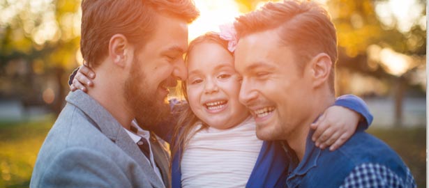 Deux hommes gais donnent une accolade à leur jeune fille.