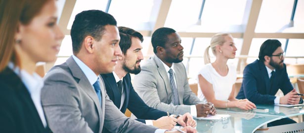 Un groupe de professionnels assis à une table de conférence, à l’écoute.